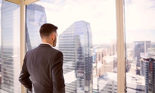 Mann sieht aus dem Fenster und sieht unterschiedliche Gebäude